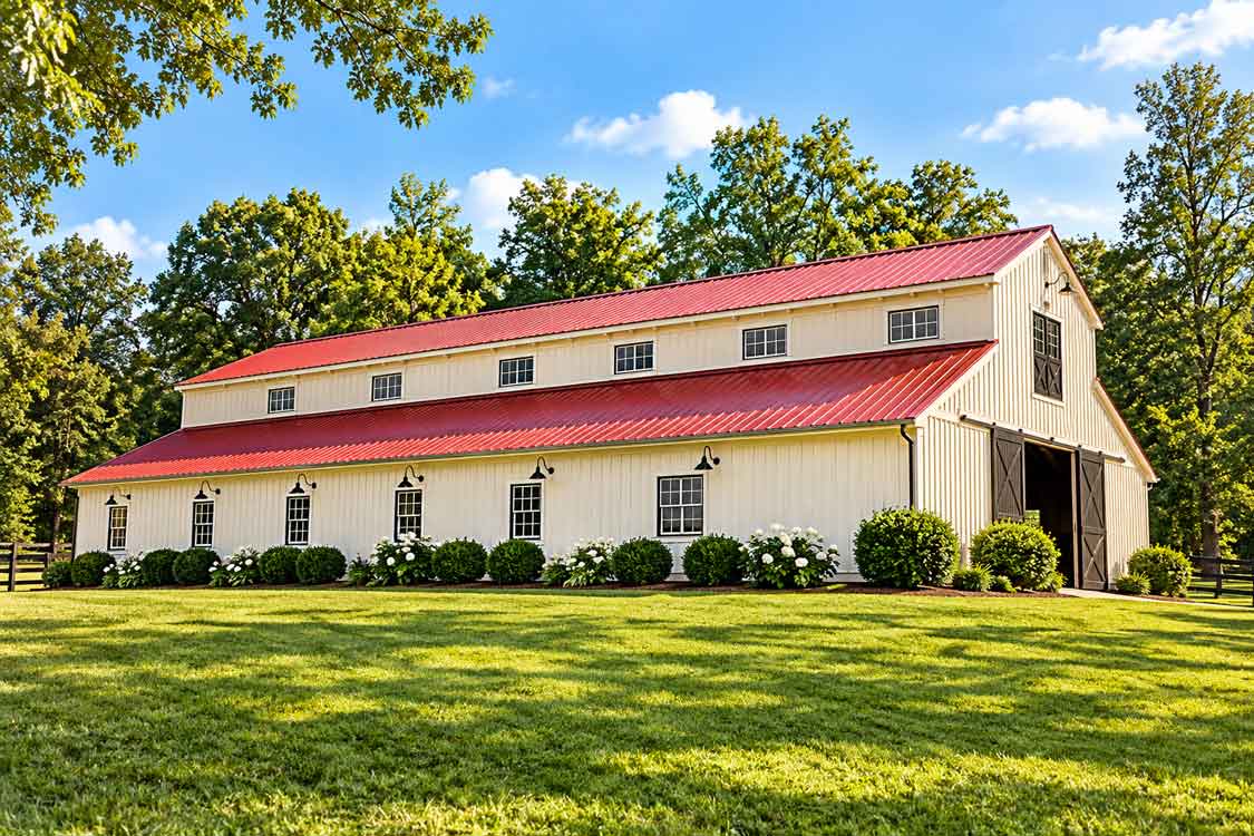 Horse stable with red roof, white exterior, and fenced grounds on a Central Virginia equestrian property