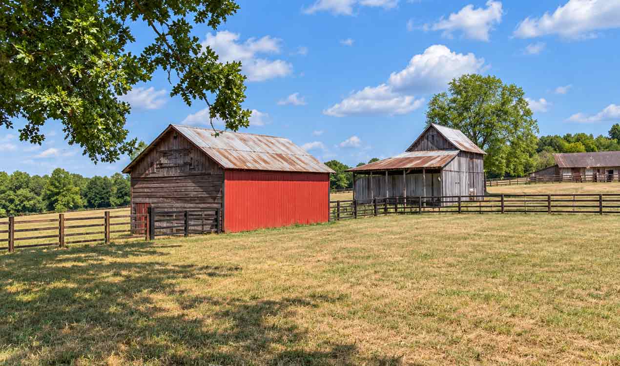 Fluvanna County horse farm with weathered barns, red barn doors, fenced pastures, and open grazing land