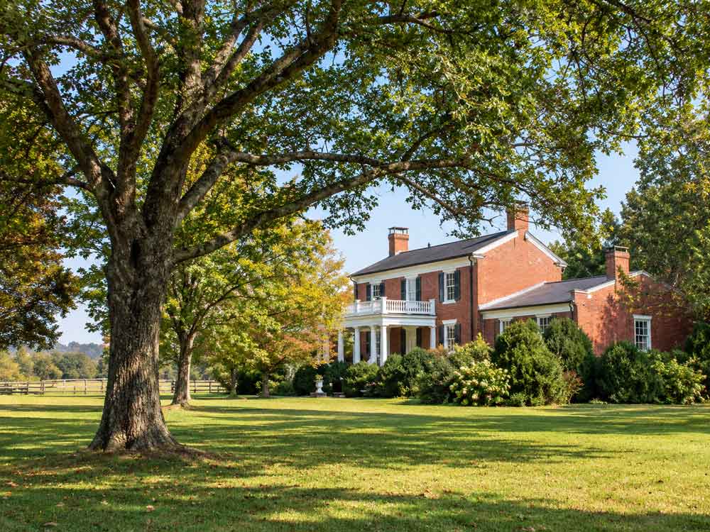 Historic brick home on a horse farm with fenced pasture and mature trees in Keswick, Virginia