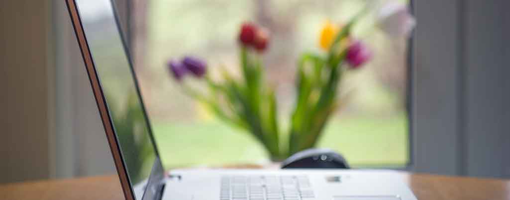 Laptop computer on table with flowers.